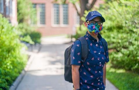 student wearing mask with unh hat 