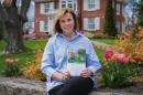 Jan Dean sitting outside of the president's house with her book